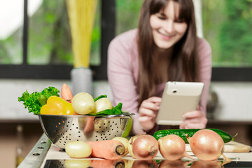 Girl look at the tablet.Young Woman Cooking in the kitchen at home. Healthy Food.