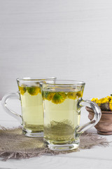 Two cups of herbal tea with coltsfoot (or Tussilago) flowers  
