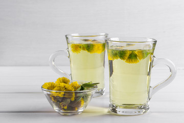 Two cups of herbal tea with coltsfoot (or Tussilago) flowers  