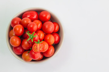 Fresh cherry tomatoes are in a cup on a white background.