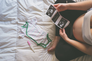 Pregnant woman looking at ultrasound scan of baby, top view