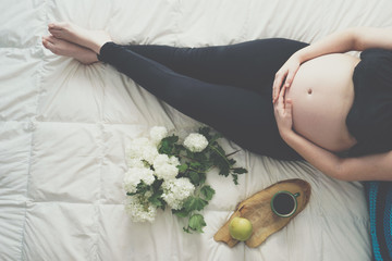 Pregnant woman is lying in bed, top view