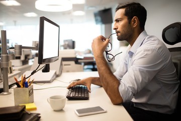 Thoughtful businessman using computer in office