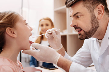 Confident doctor looking into mouth of his patient