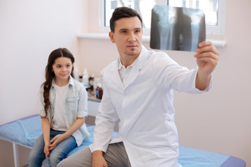 Obraz premium Serious professional doctor examining an X ray photo