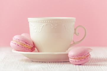 pink macaroons homemade and a cup of coffee on pink background toned
