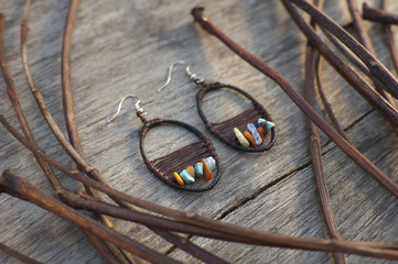 Handmade earring in boho style made with eco materials lying at wooden background with natural tree twigs © Nozyer