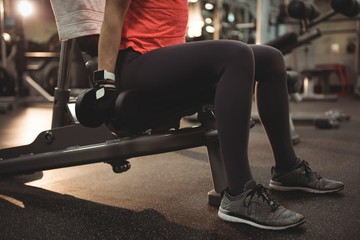 Fit woman exercising with dumbbells on a machine