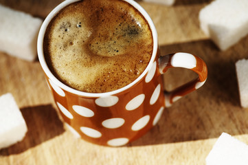 Cup of coffee and sugar cubes on wooden board