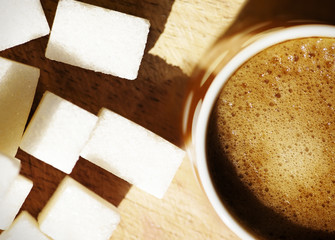 Cup of coffee and sugar cubes on wooden board