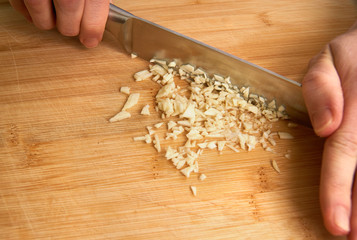 Man's hands cutting fresh garlic in the kitchen, preparing a meal for lunch. With copyspace.