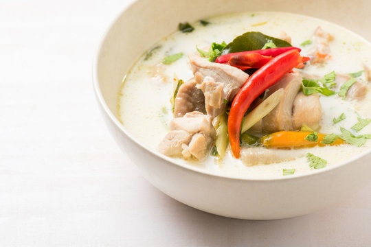 Thai chicken soup in coconut milk on white wooden background