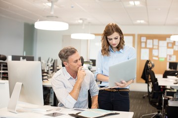 Business colleagues working together on laptop at desk