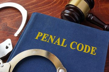 Cuffs and book with the title Penal code. Criminal law concept. - obrazy, fototapety, plakaty