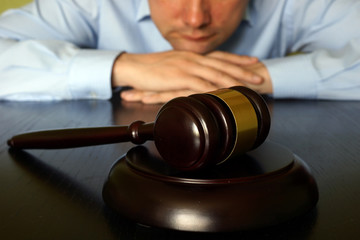 Justice concept. Man is sitting at the table opposite gavel.