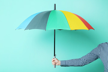 Colorful umbrella in male hand on green background