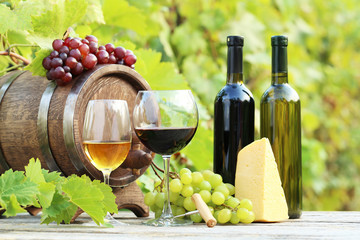 Fototapeta premium Wine in glasses with bunch of grape and cheese on wooden table