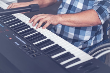 Young disabled man playing musical keyboard in the studio