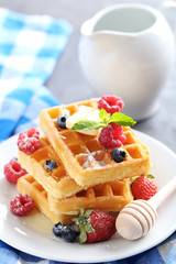 Homemade waffles with berries in plate on grey table