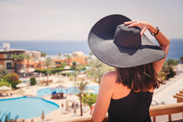 woman in black hat looks at the pool and sea in Egypt