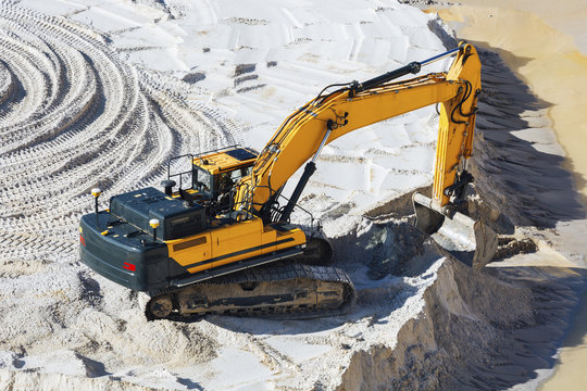 Schaufelbagger in Sandgrube schaufelt tr&auml;gt Sand ab  