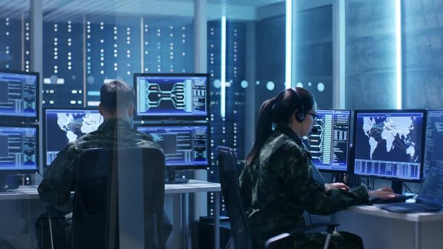 Male and Female Military IT Technicians Working on Computers with Multiple Displays Showing Various Information. Possible Surveillance, Army Maneuvers. Shot on RED EPIC-W 8K Helium Cinema Camera.