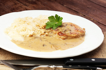 Delicious rice with chicken and vegetables on plate on wooden table