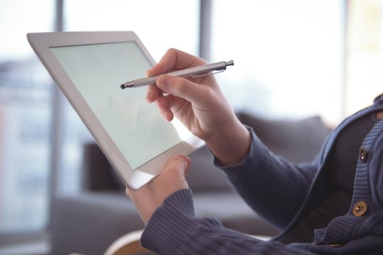 Woman using digital tablet while sitting at home