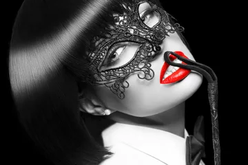Cercles muraux Photo du jour Femme sexy en masque, fouet sur les lèvres rouges, coloration sélective, bdsm