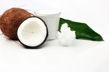 Coconut with leaves and coconut oil in jar on wooden background