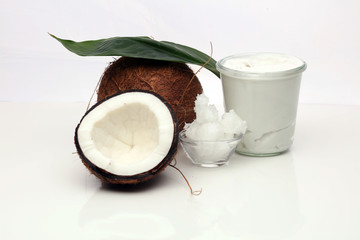 Coconut with leaves and coconut oil in jar on wooden background