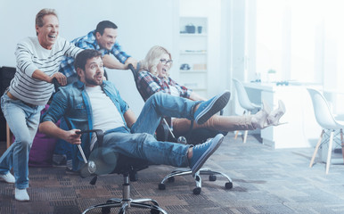 Office workers having fun with a swivel chair