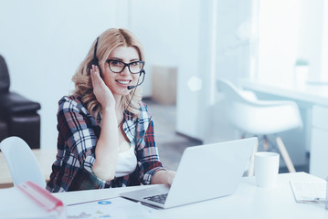 Overjoyed beautiful female support operator sitting in the office