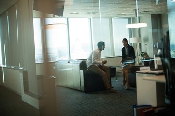 Business colleagues interacting while sitting on sofa in office