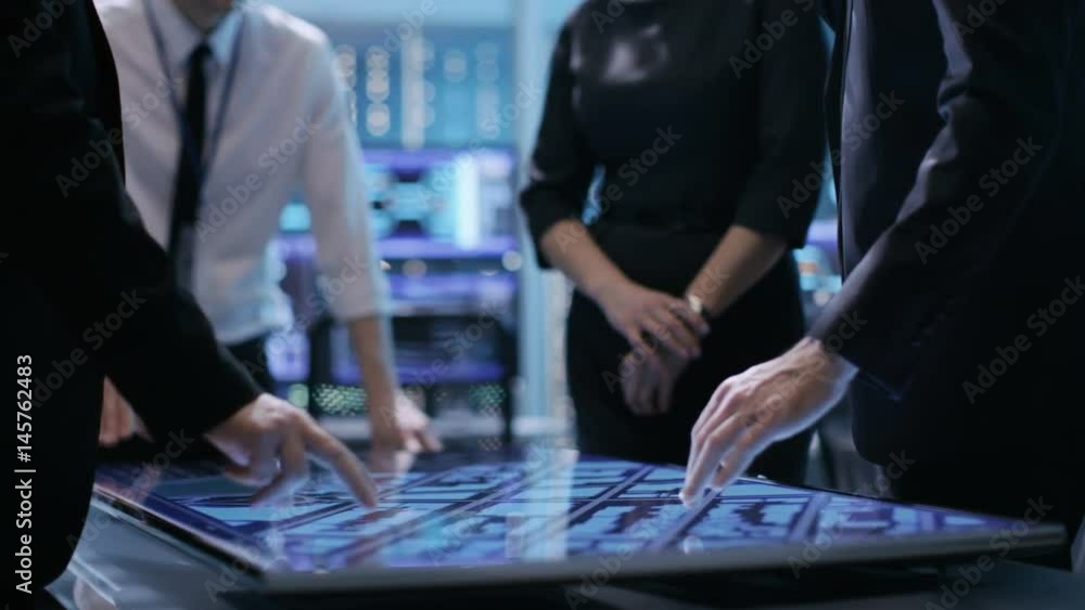 Poster close-up of surveillance agency's agents hands on interactive touchscreen table, tracking dangerous 
