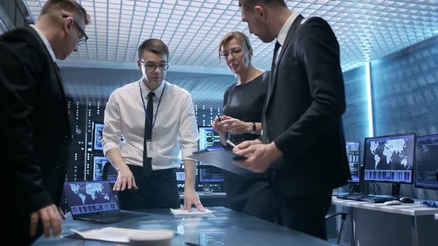 Team of Government Agents Tracking Fugitive with Help of Touchscreen Interactive Table in State of the Art Monitoring Room Full of Computers with Animated Screens. Shot on RED EPIC-W 8K