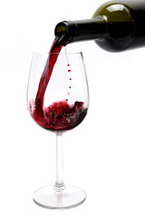 Red wine poured from a bottle in a elegant crystal goblet, isolated on white background.