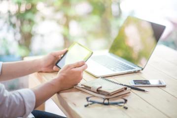Business man holding tablet and working with laptop and smart phone on wooden office desk in...