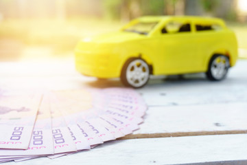 Thai banknotes on white wooden with toy car background.concept of buying car