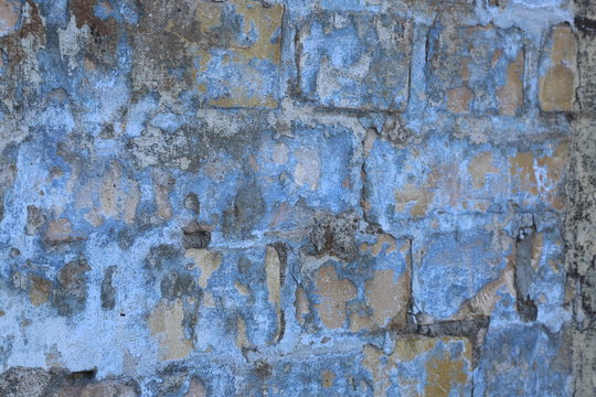 Eine Steinmauer mit abblätternder blaue Farbe