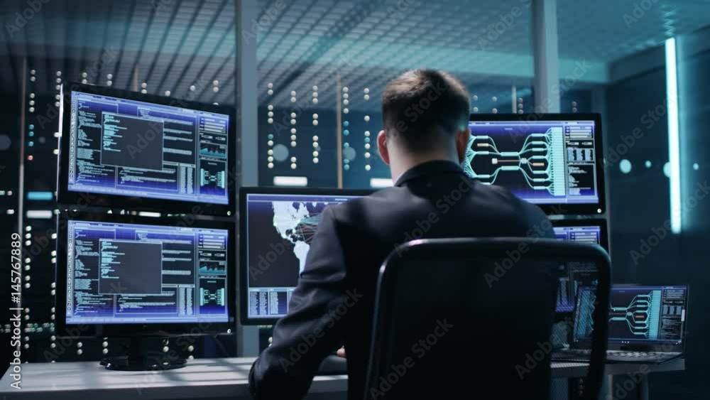 Poster back view of technical controller/ operator working at his workstation with multiple displays. possi