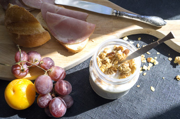 Breakfast, yogurt, plums, grapes on a wooden Board