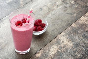 Raspberry smoothie in glass on wooden table
