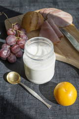 Breakfast, yogurt, plums, grapes on a wooden Board