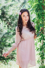 Outdoor fashion photo of beautiful young happy smiling woman surrounded by flowers. Spring blossom