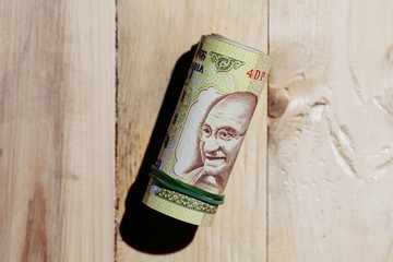 Indian hundered rupees roll against a wooden background.