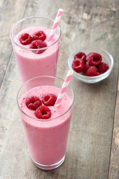 Raspberry smoothie in glass on wooden table
