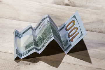 A conceptual shot of us dollar bill folded as to show an upward trend, growth in a business.