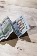 A conceptual shot of us dollar bill folded as to show an upward trend, growth in a business.