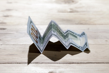 A conceptual shot of us dollar bill folded as to show an upward trend, growth in a business.